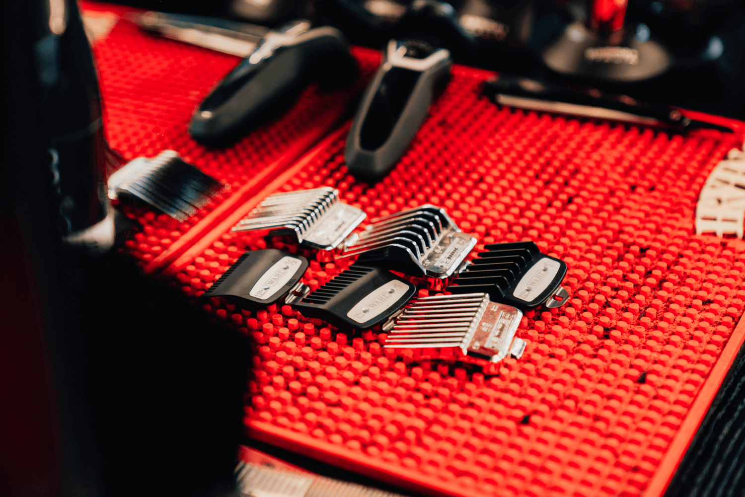 Clippers and attachments laying on top of a red mat.