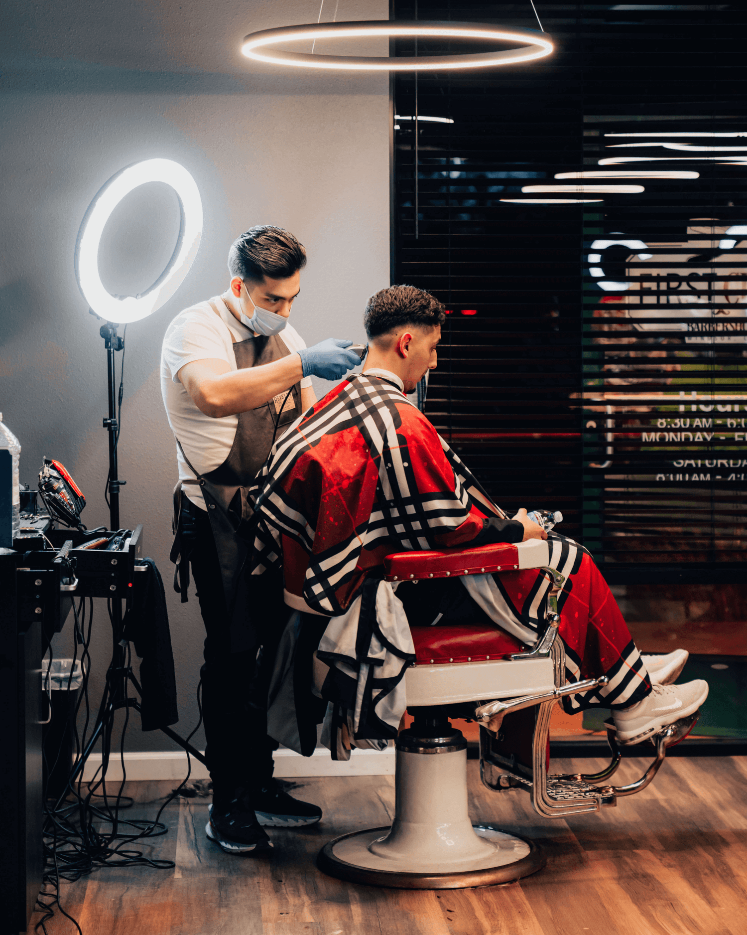 Barber giving a client a haircut with a bright white light behind them.