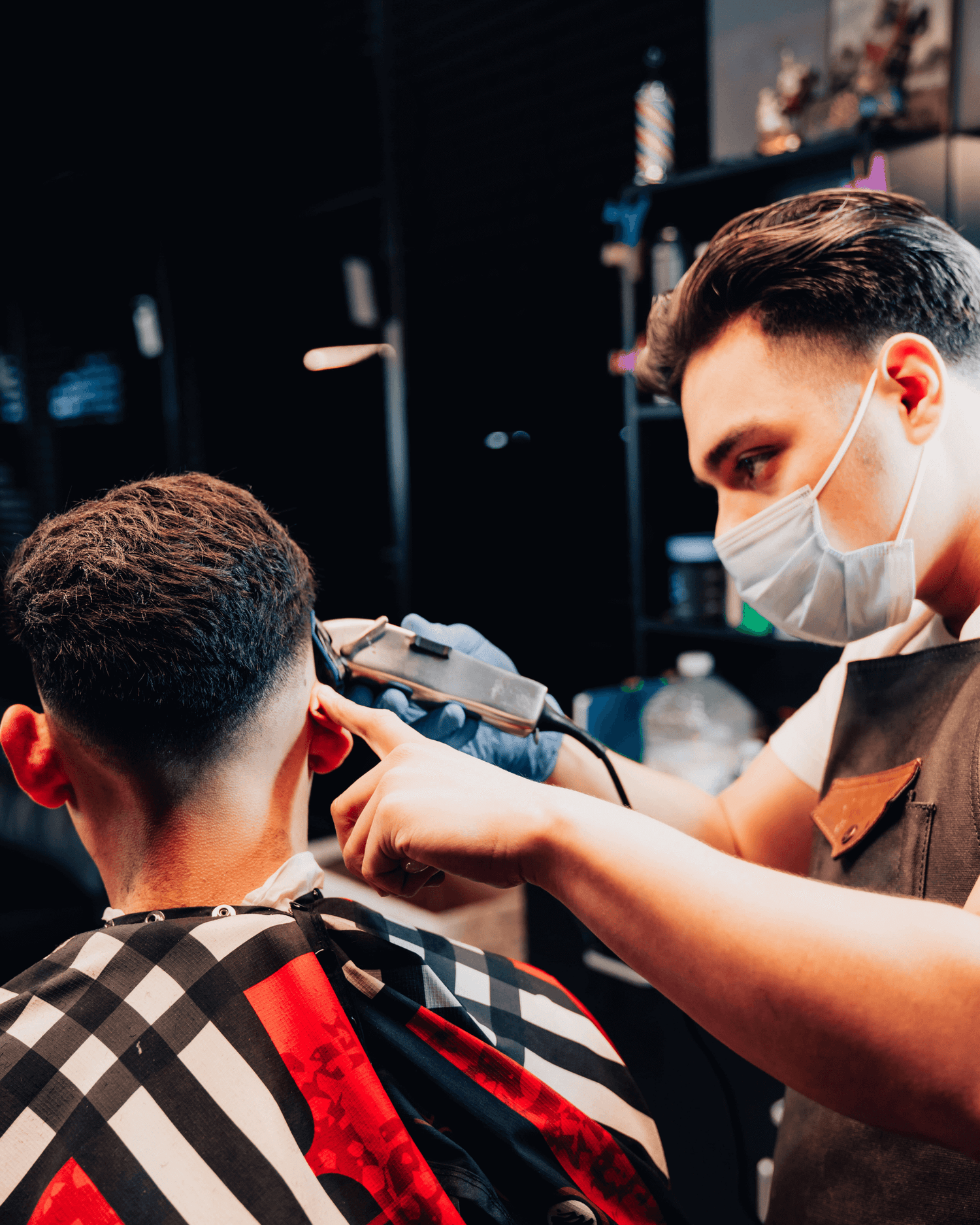 Barber cutting hair with gray clippers. 