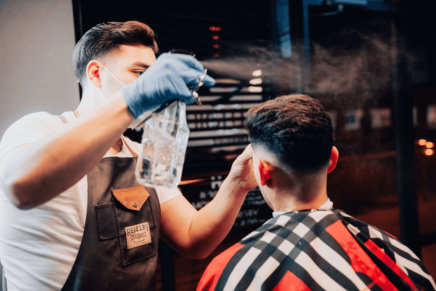 Barber spraying customer with water to prepare for a haircut.