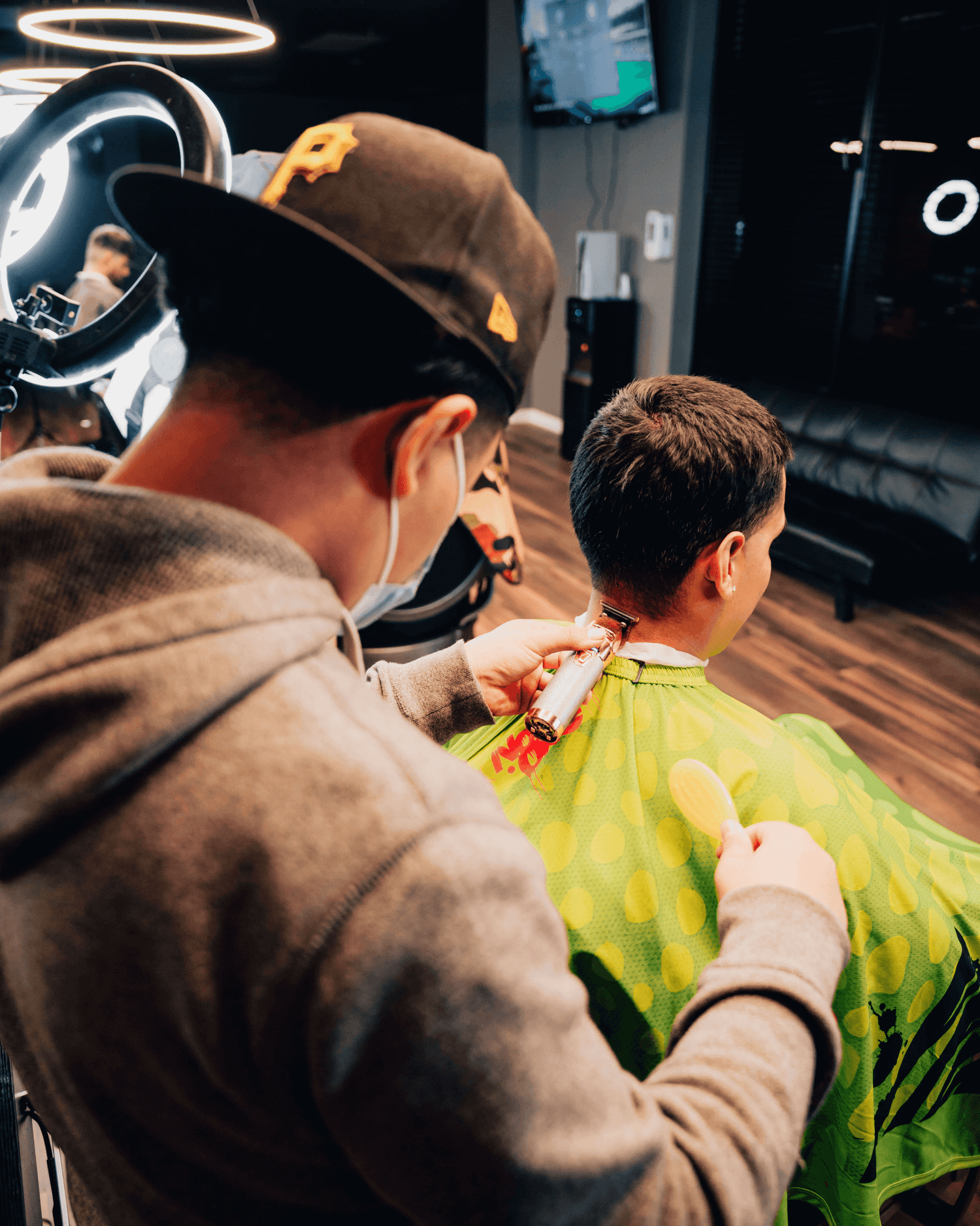 Barber shaping the back of someones hair with clippers.