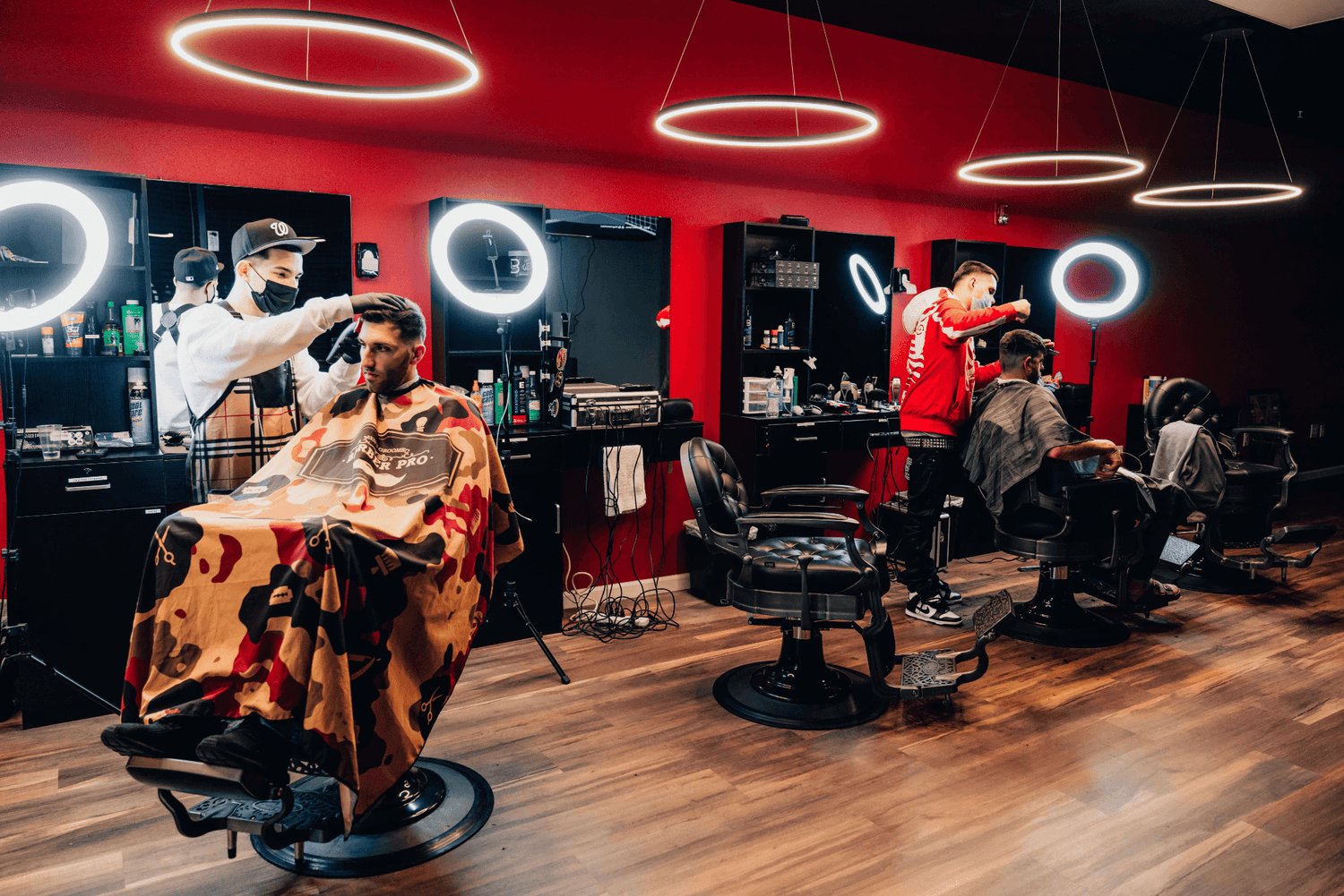 Two barber cutting hair with bright lights behind them.