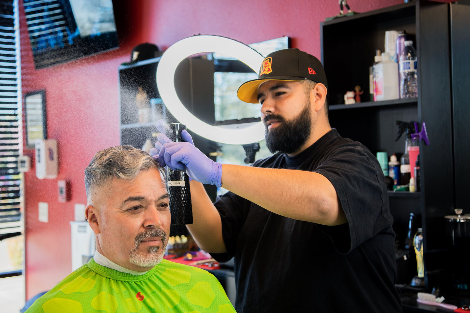Barber in a black shirt spraying client with a water spray for a haircut