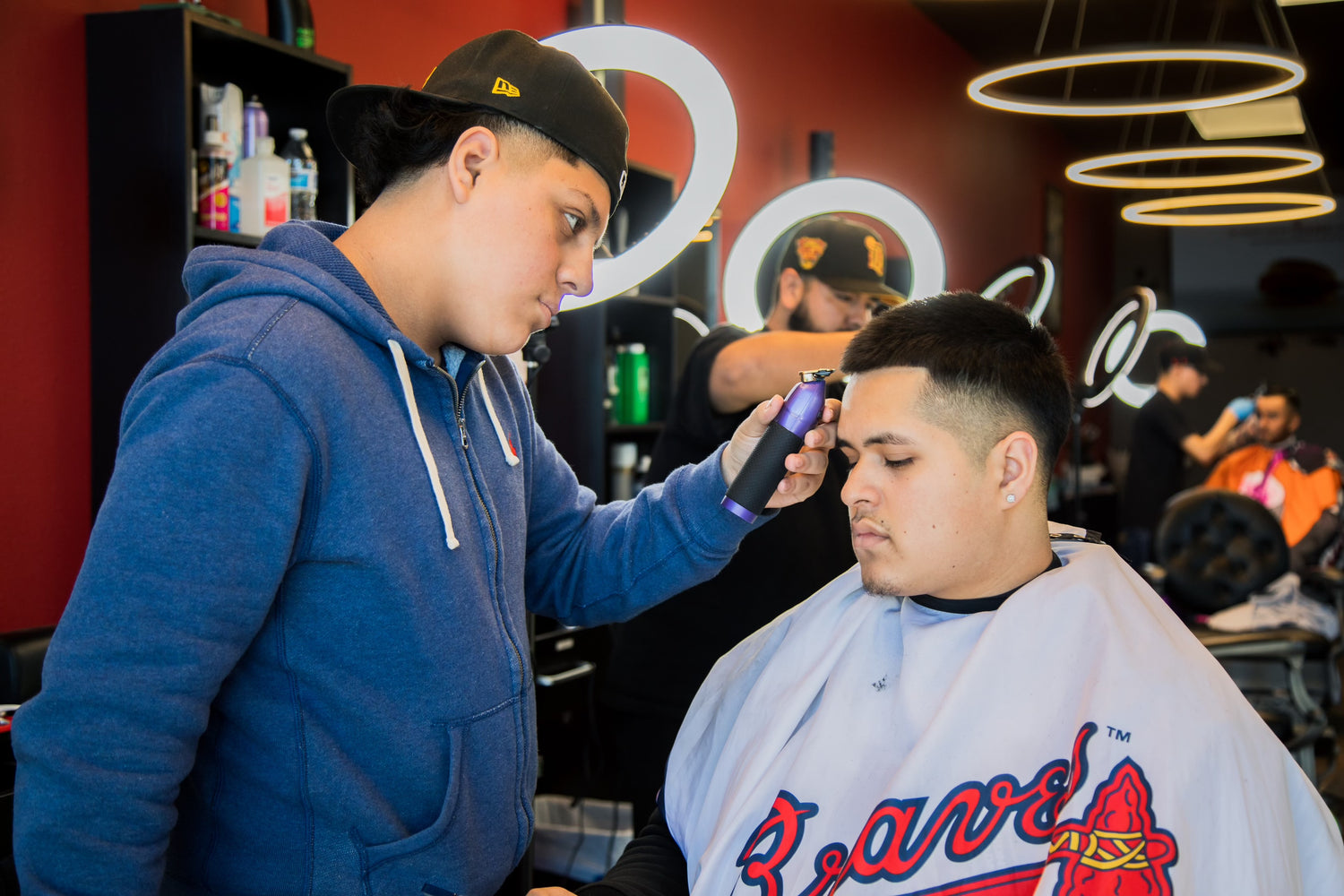Barber in a blue sweater giving a client a haircut