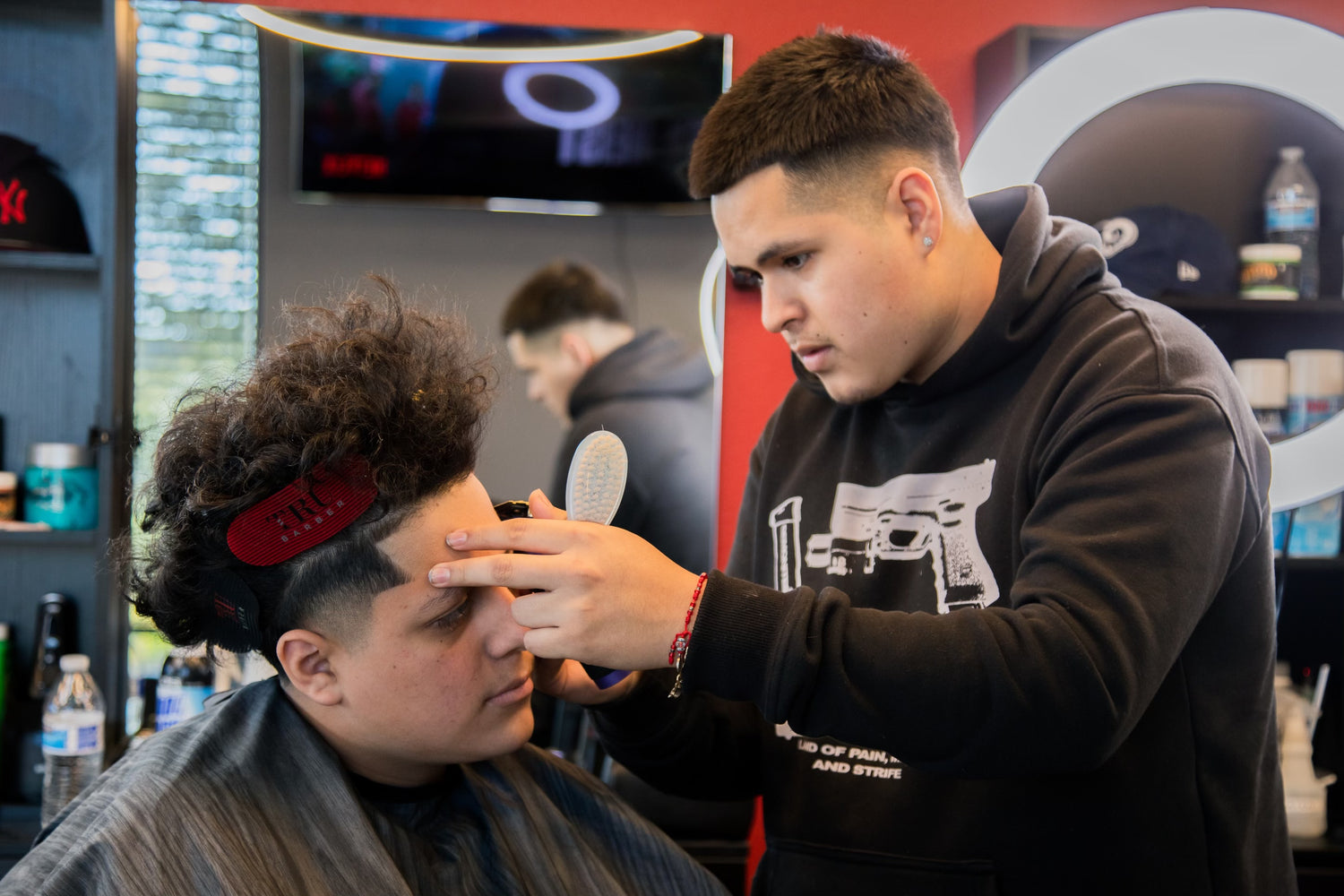 Barber in black sweater giving a client a haircut